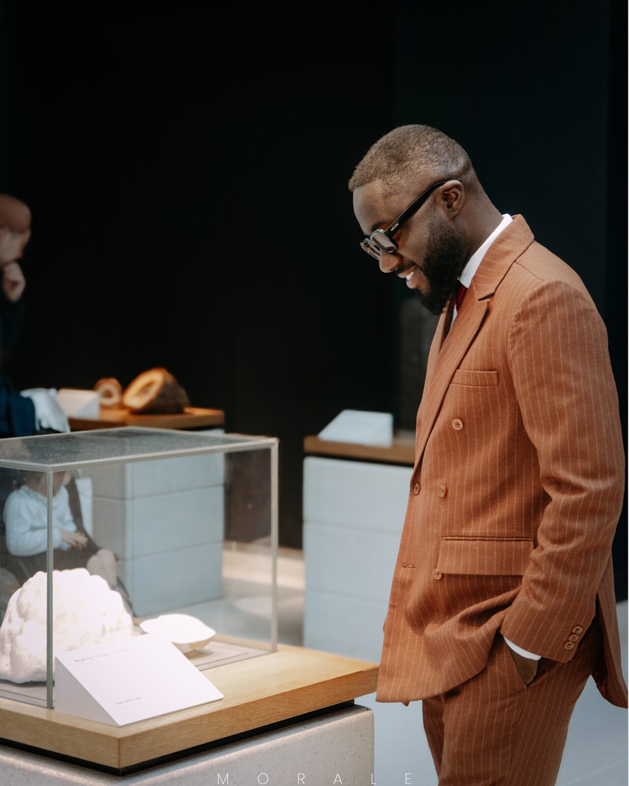 Editorial frame of a suited man browsing a lit display case